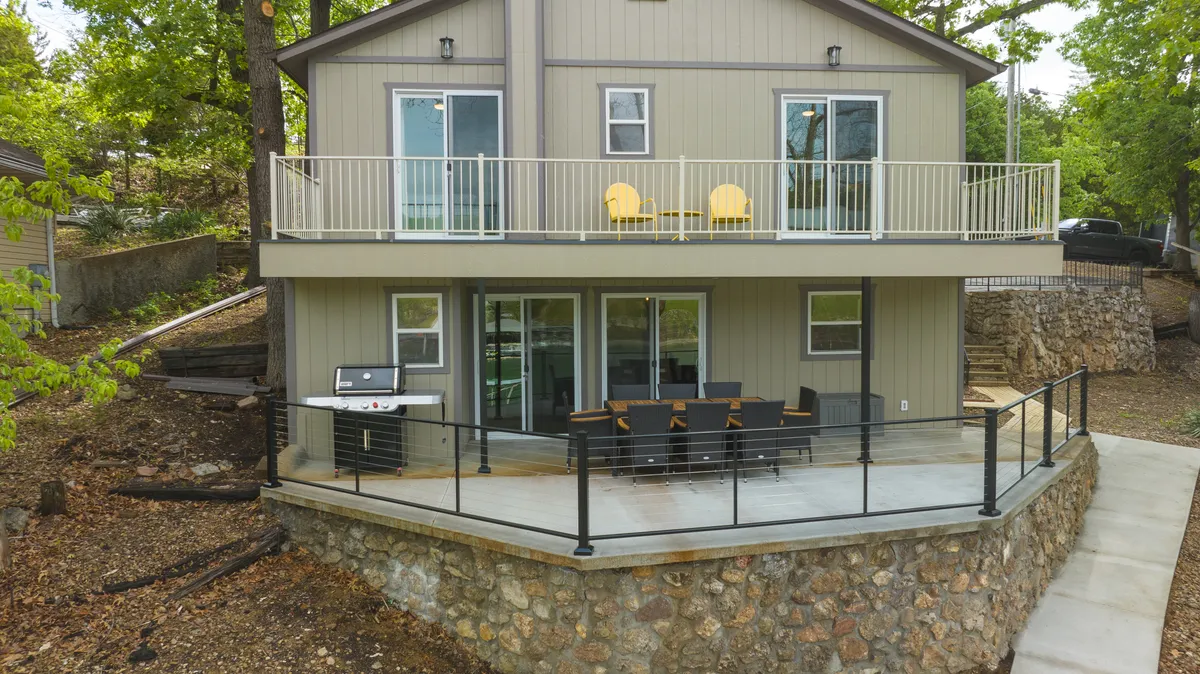 A welcoming balcony space featuring bright yellow chairs, an outdoor dining set, and a grill. The setup invites guests to enjoy meals outside while taking in lake views or relaxing in the fresh air.