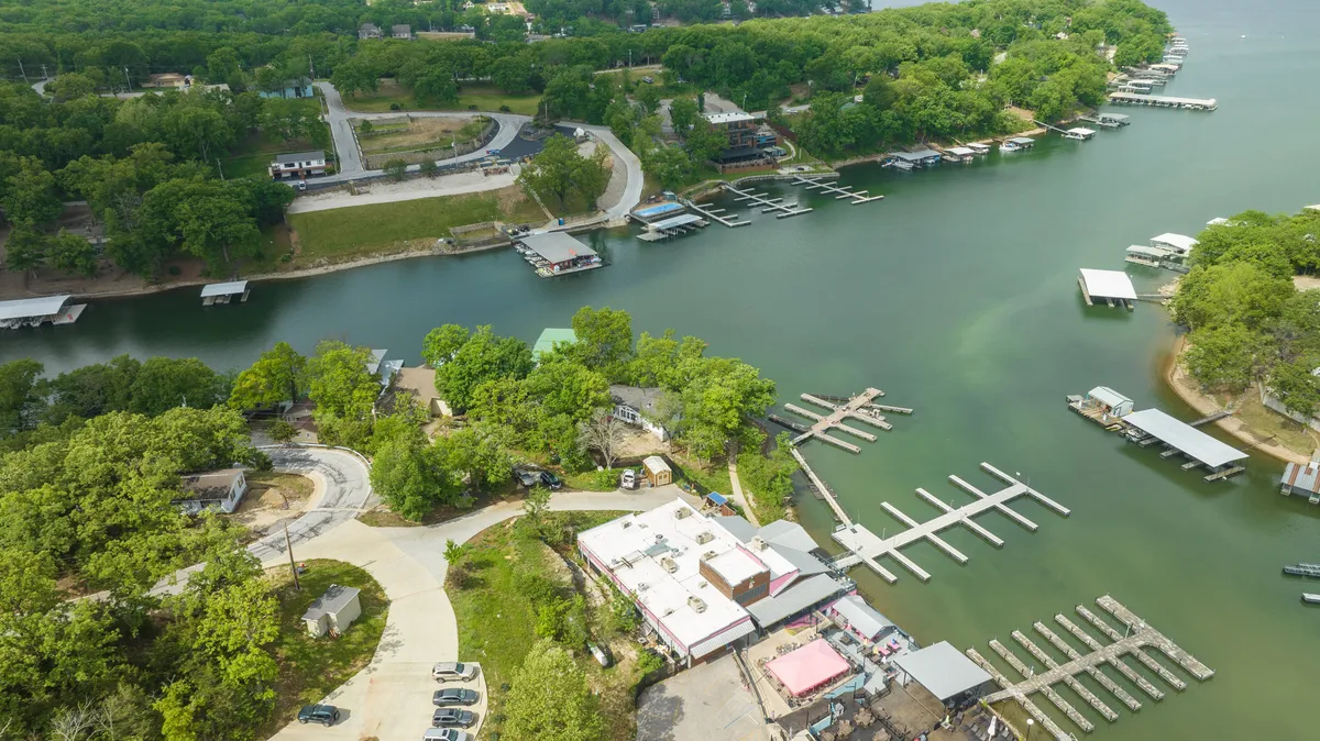 A bright, bustling marina with boats docked along the shoreline, surrounded by green trees and waterfront properties. The scene suggests opportunities for boating, fishing, and relaxing by the water, highlighting the area's outdoor recreation.