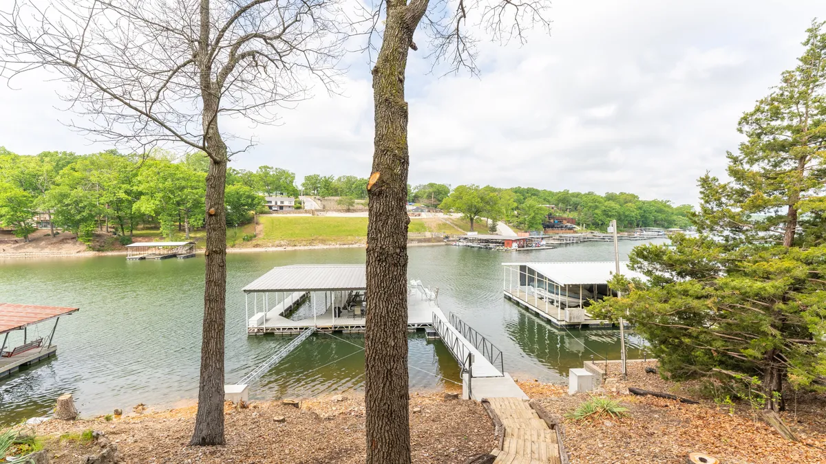 A scenic view of the lakefront featuring boat docks, a tranquil shoreline, and lush trees, all set along a winding pathway perfect for leisurely walks or morning coffee by the water.