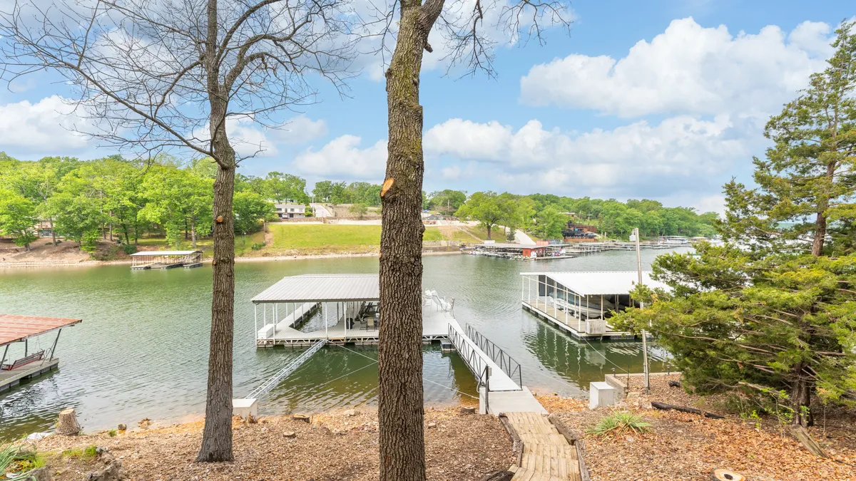 This exterior shot captures the lake, several docks extending into the water, and a backdrop of mature trees. The composition hints at the social potential of the docks for group gatherings, early morning fishing, or evening relaxation. The relaxed mood encourages thoughts of both energetic activity and peaceful retreat.