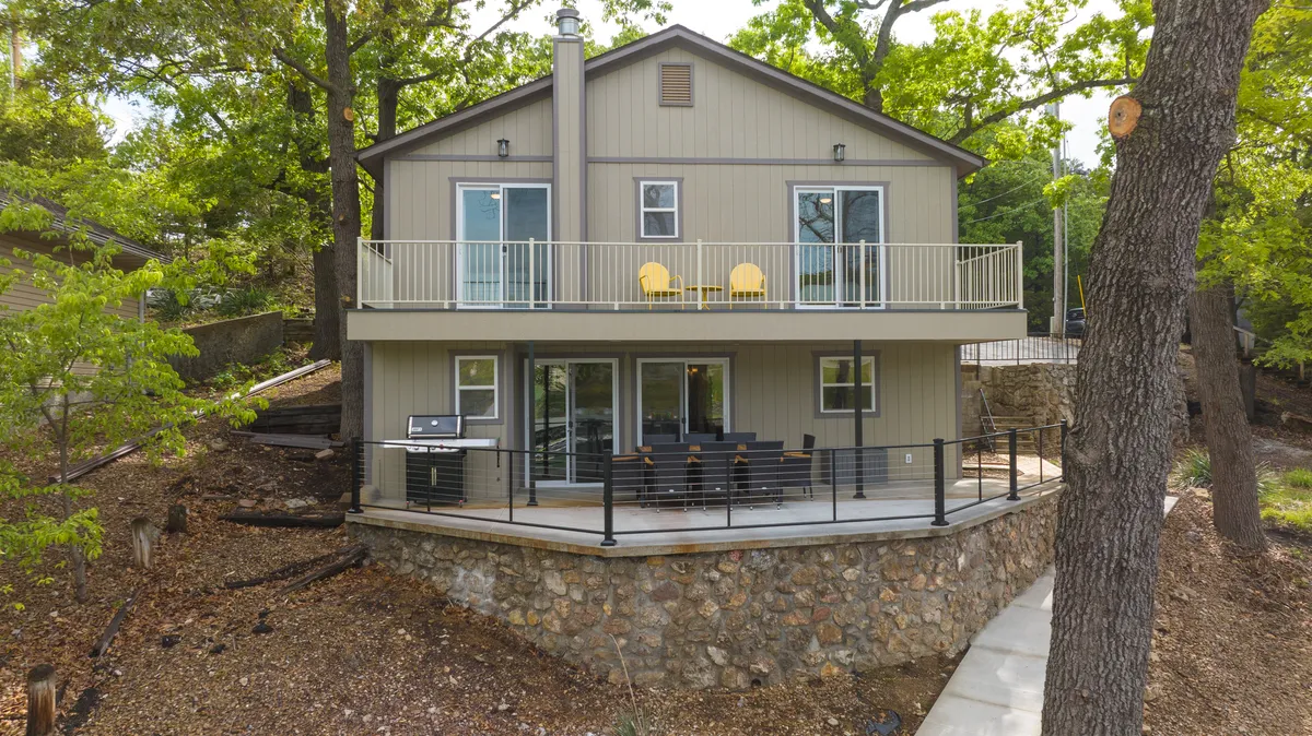 A welcoming exterior balcony with cheerful yellow chairs, large windows, and a stone wall. The setting is ideal for gathering with friends, enjoying morning coffee, or relaxing after a day of exploring the region.