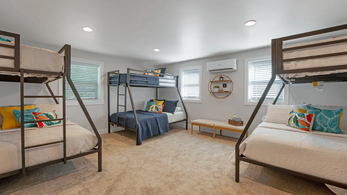 A playful bedroom featuring bunk beds with colorful pillows, a decorative wall circle, and bench seating. The mood is relaxed and playful, making it perfect for kids or groups, and offering an inviting space for bonding and late-night conversations.