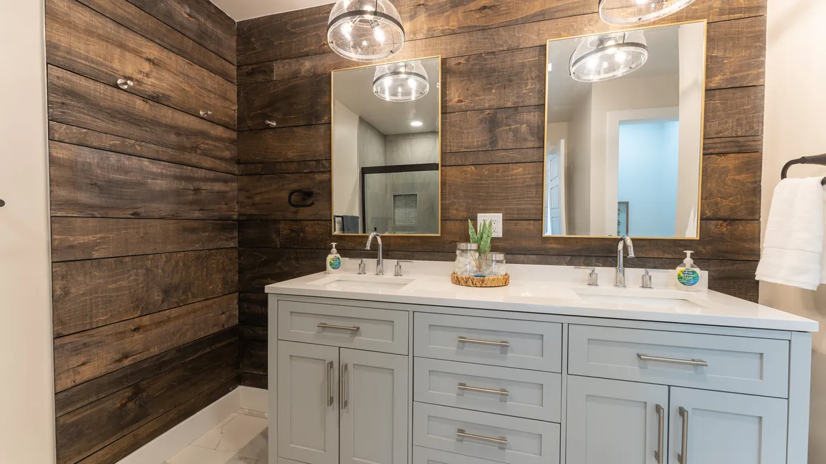 A bright, modern bathroom with a double vanity, large mirrors, and a wooden accent wall. The clean lines and spacious layout evoke a soothing, spa-like ambiance for personal grooming and relaxation.