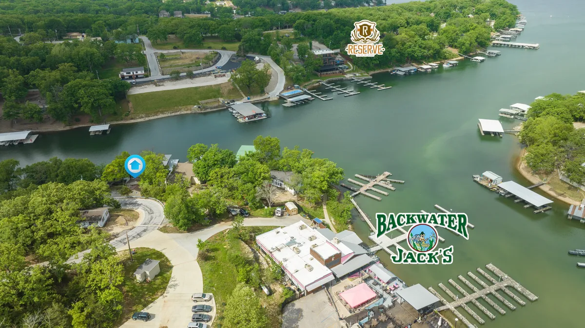 A waterfront view of Backwater Jack’s restaurant, with its lively docks, vibrant outdoor spaces, and lush greenery in the backdrop. People are enjoying dining, boating, and socializing, all just moments from the home.
